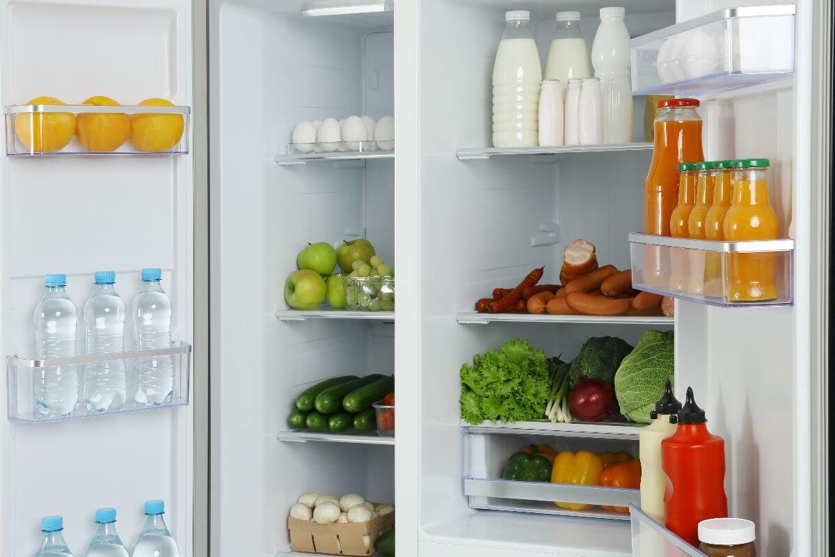 opened refrigerator filled with fruits, vegetables, and bottles
