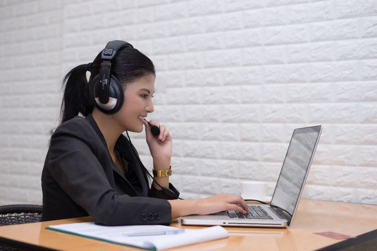 Virtual assistant wearing a headset while providing remote support on a laptop.