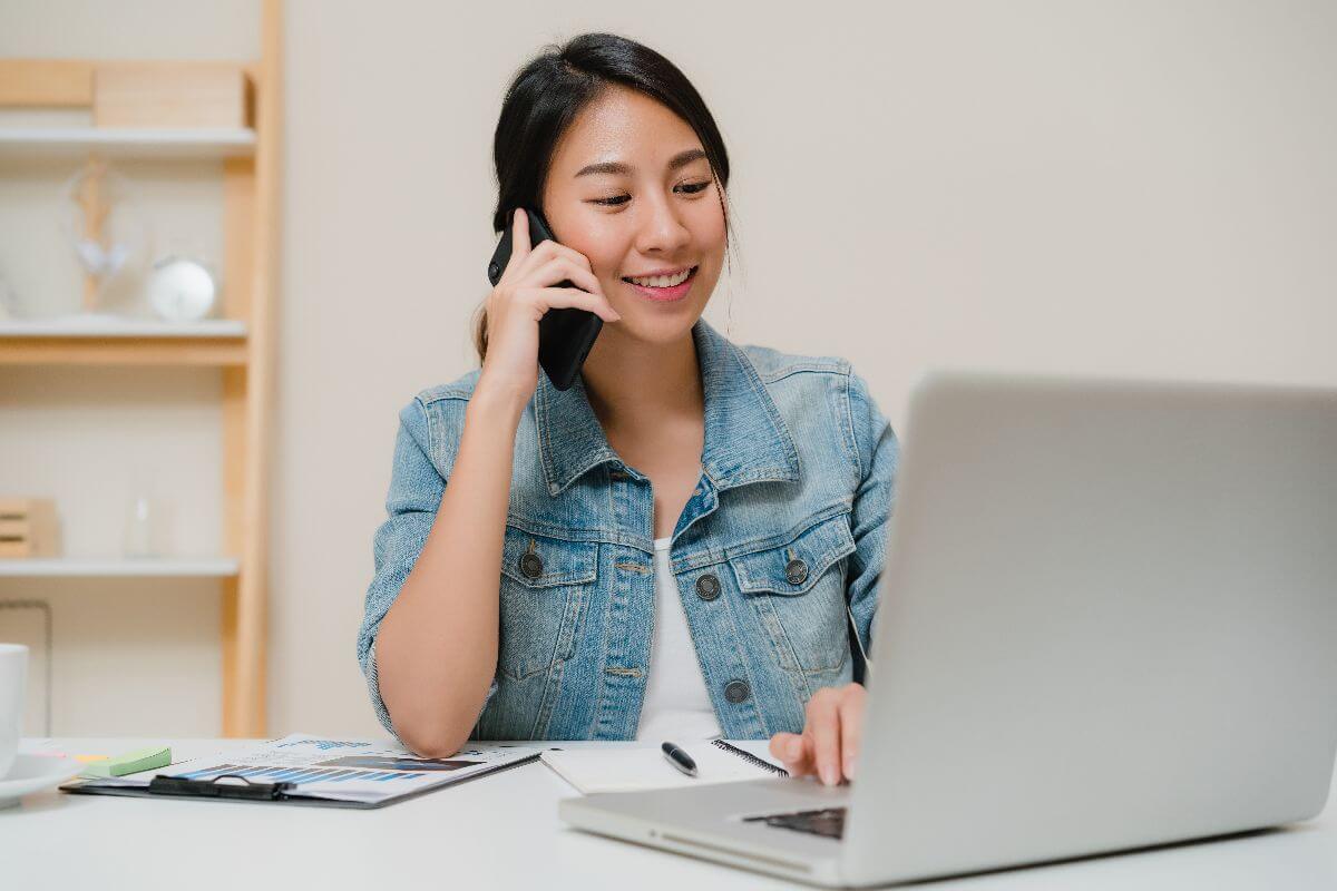 Virtual assistant speaking with a client on the phone while working on a laptop.