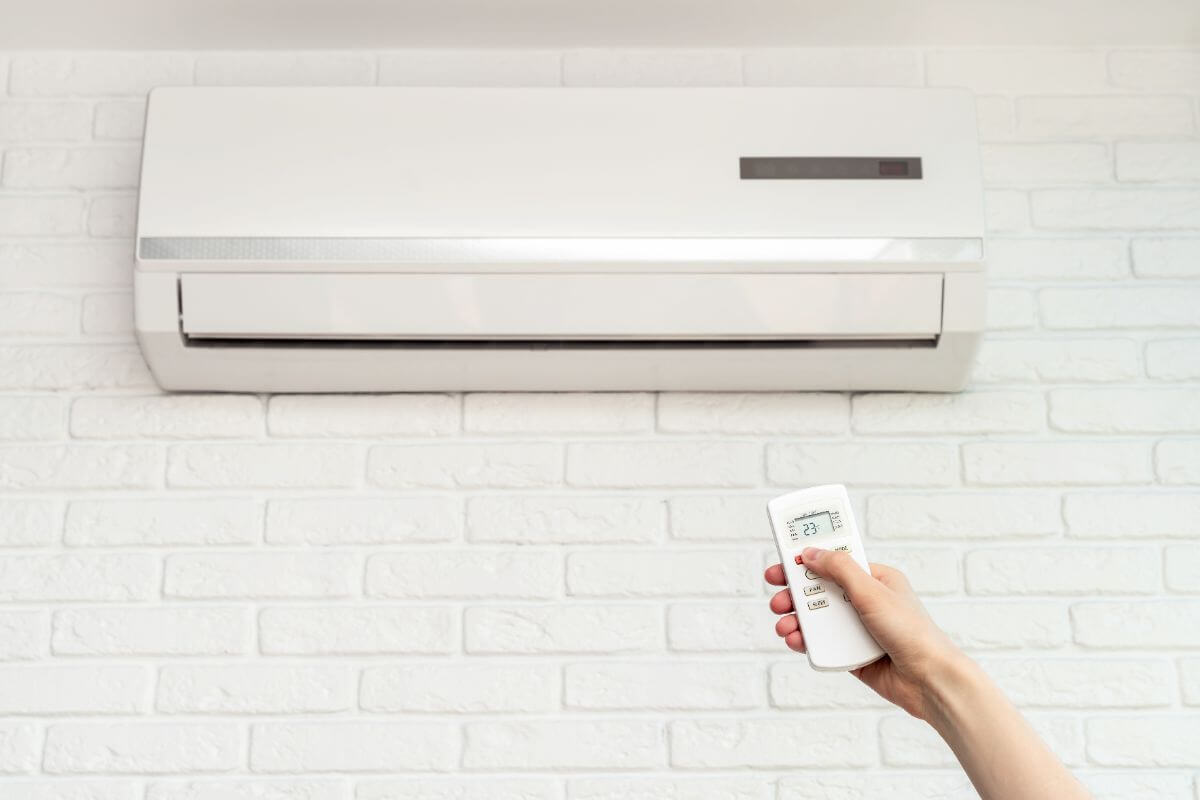 hand turning on a white air conditioner in room
