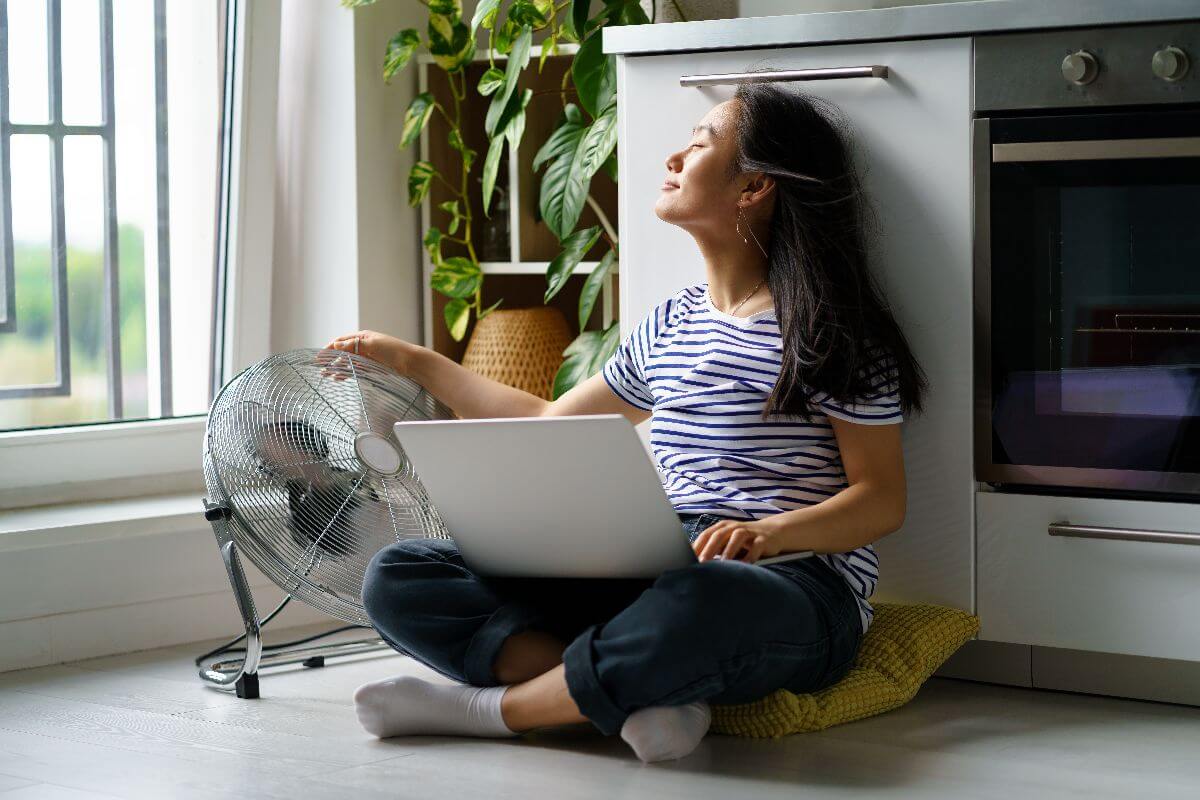woman on floor with fan during summer