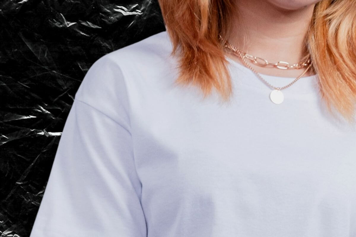 Woman with blonde hair wearing a plain white T-shirt paired with a three-layered necklace for a stylish casual look.