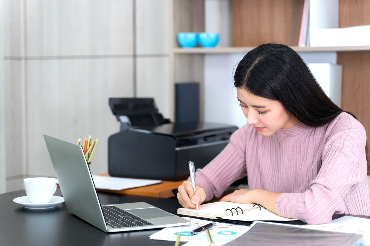 Filipina professional taking notes while working as a virtual assistant