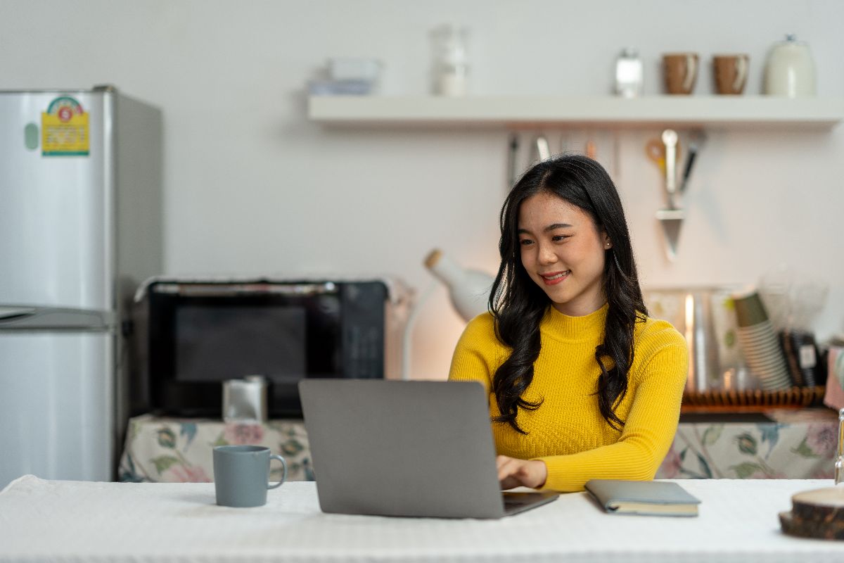 Remote worker using a laptop in a kitchen while working as a virtual assistant