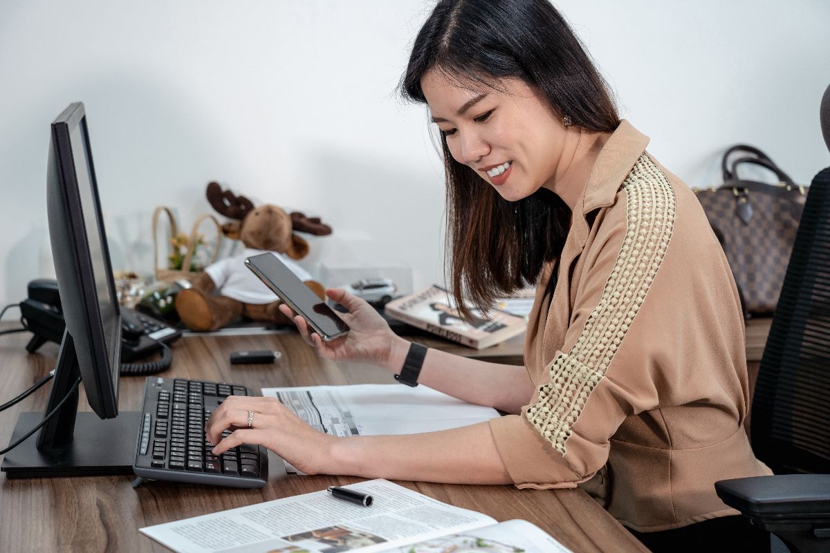Remote professional using a desktop computer and smartphone at work