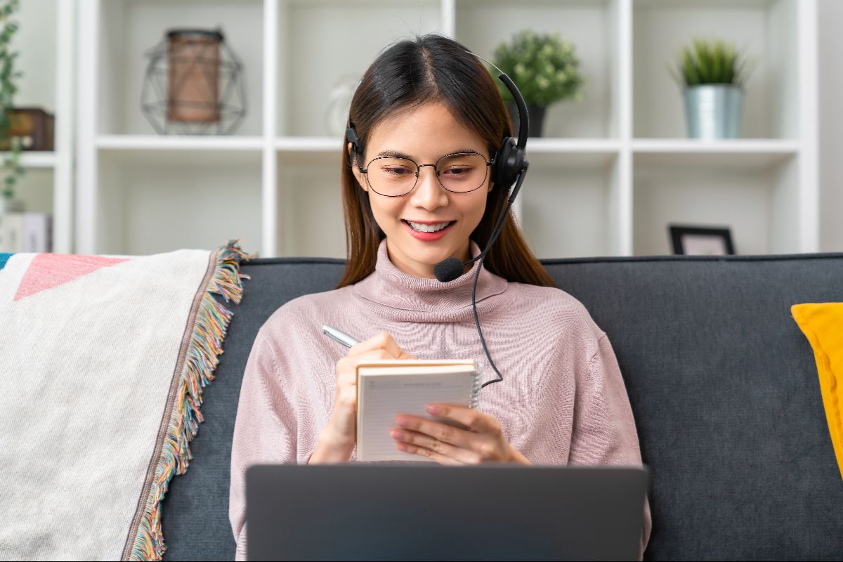 Virtual assistant wearing a headset while taking notes during remote work