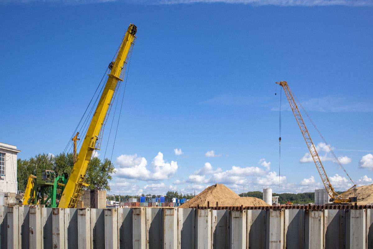 Cranes operating behind steel sheet piles at a large construction site