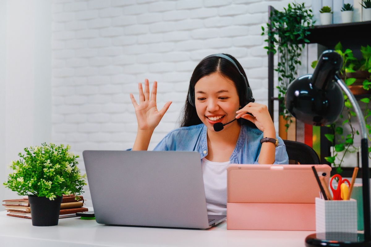 Virtual assistant waving during an online meeting from a home office