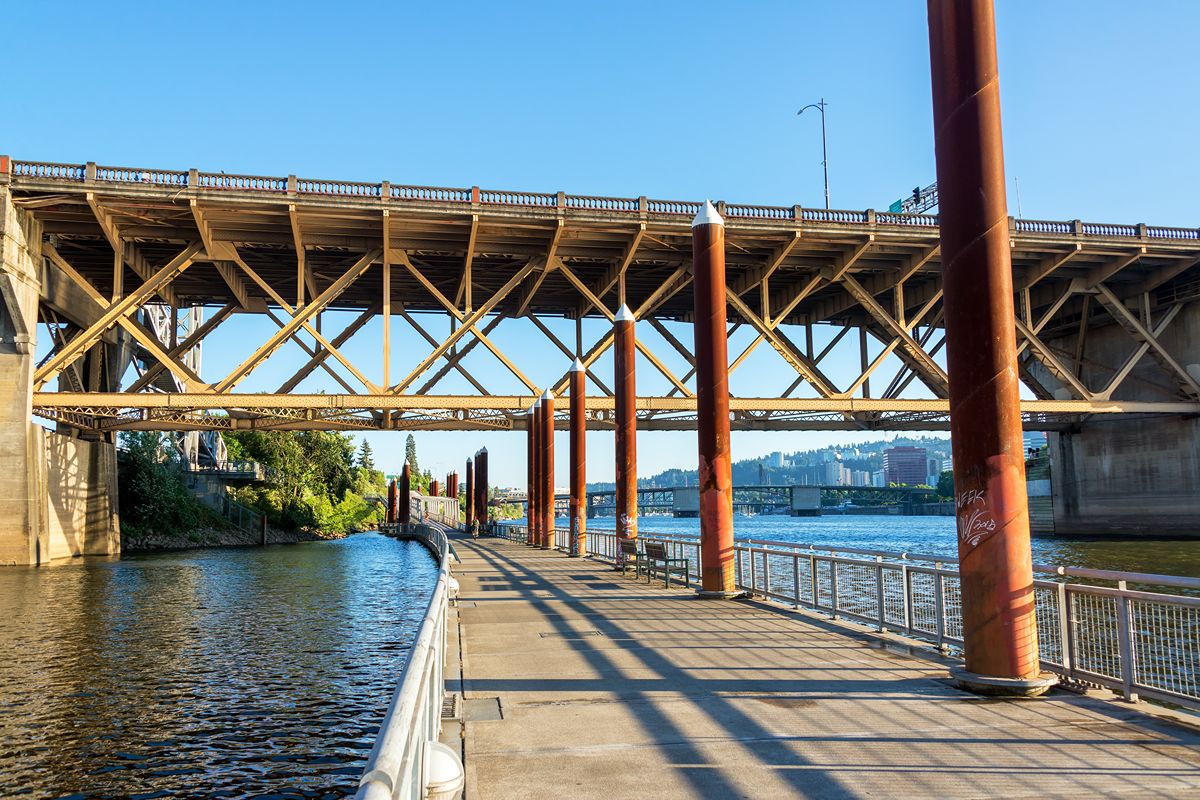 Steel sheet piles supporting a waterfront walkway beneath a large bridge