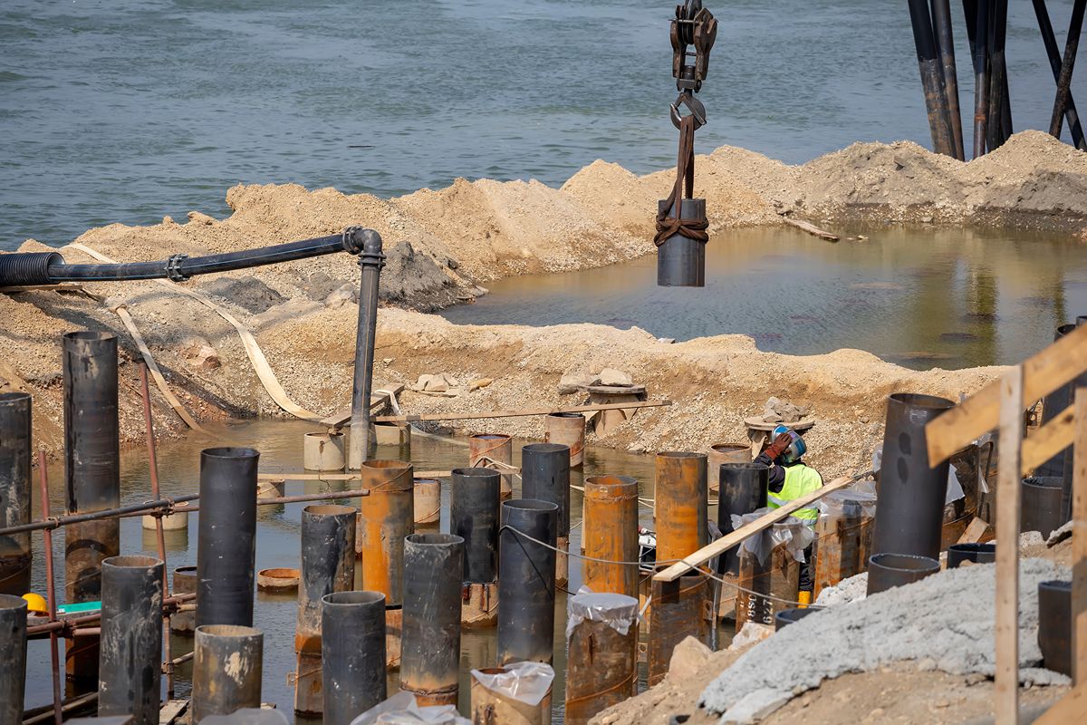 Sheet pile installation at a flooded construction site for flood control and retaining wall support