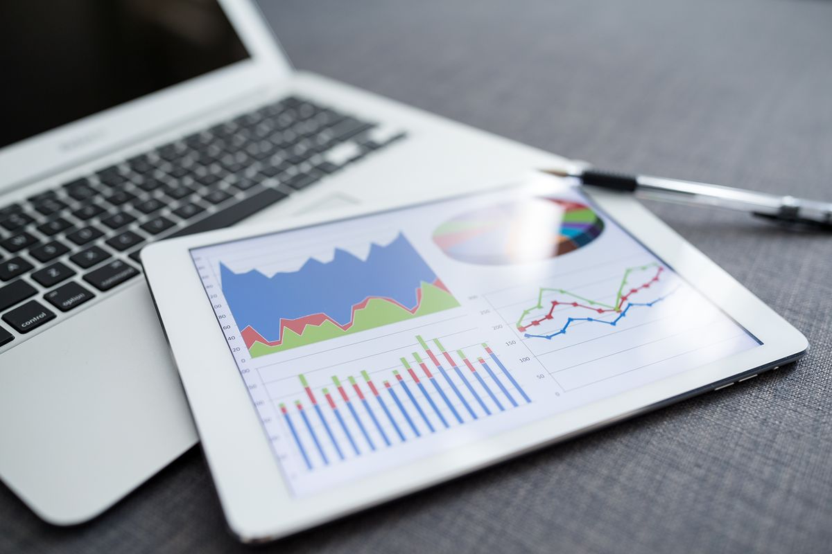 Tablet displaying SEO performance charts beside a laptop and pen on a desk