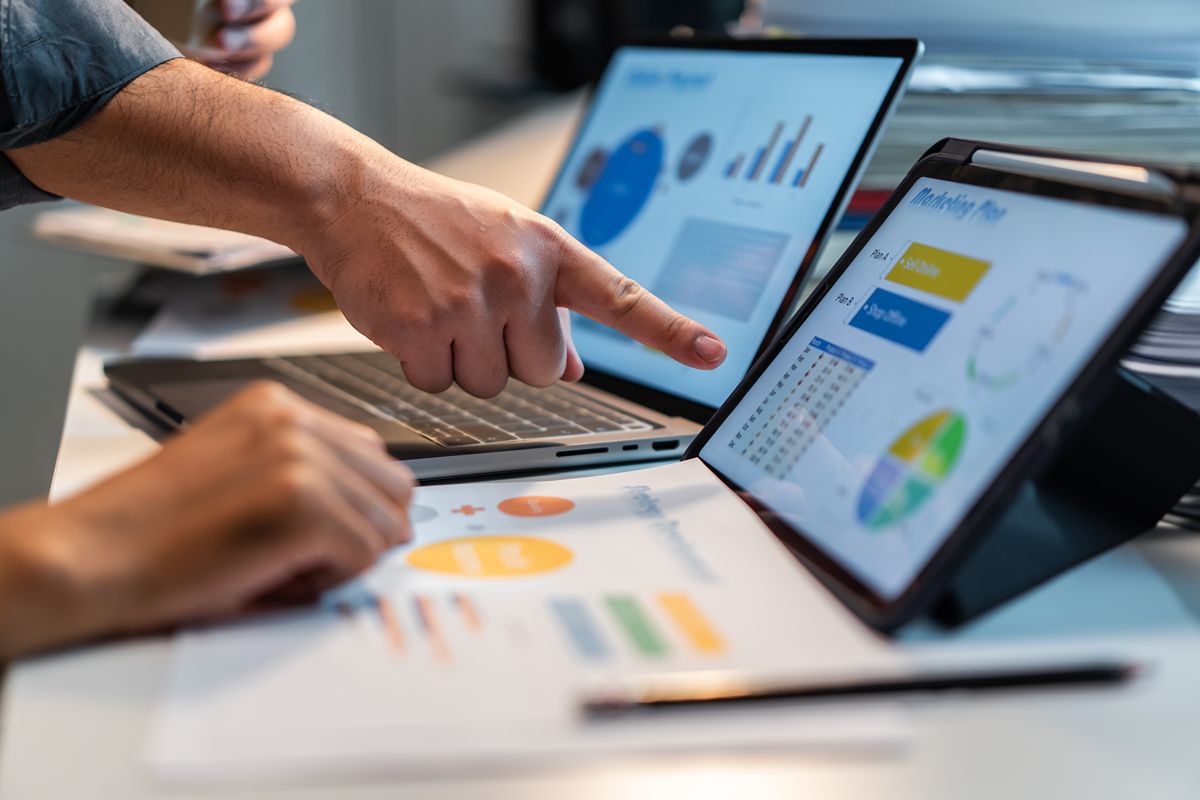 SEO professionals reviewing digital marketing charts and campaign performance across a laptop and tablet