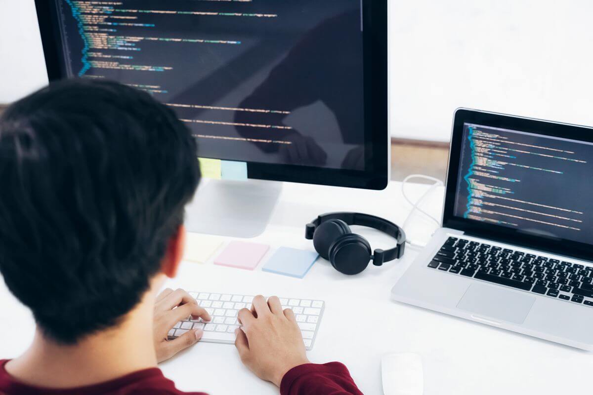 Student practices coding on desktop and laptop screens while building technical skills
