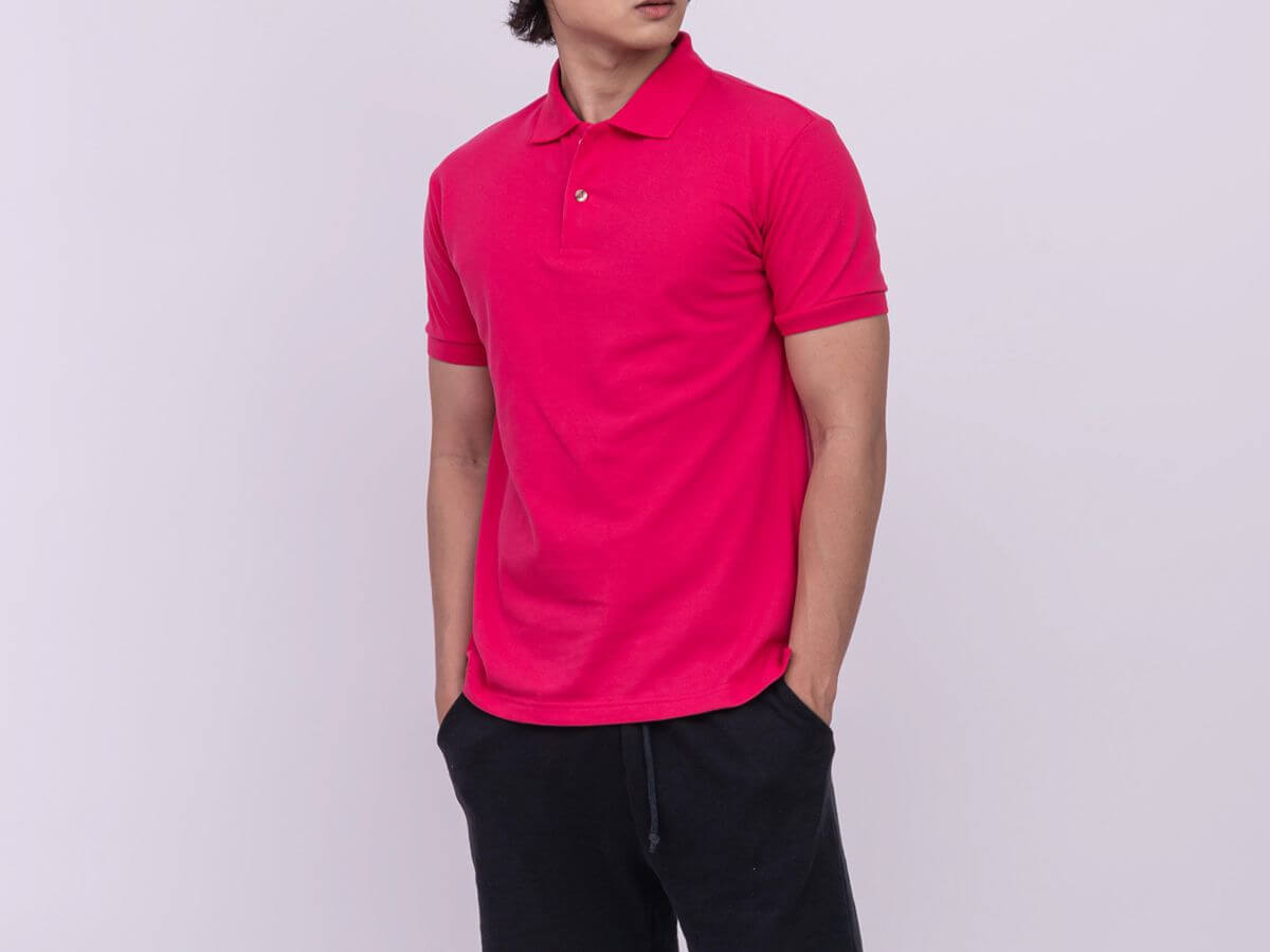 Male model wearing a bright pink breathable polo shirt in a studio setting
