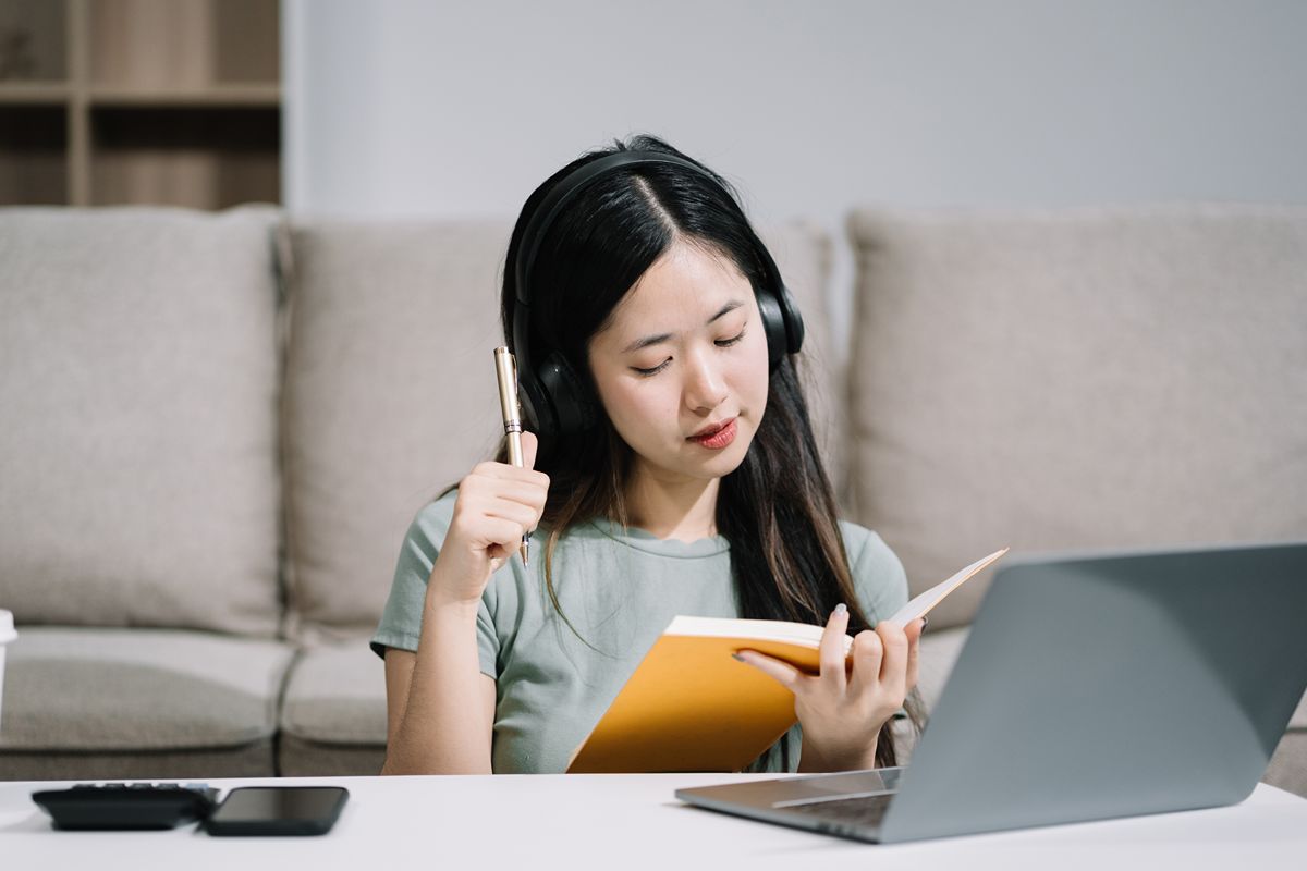Real estate virtual assistant reviewing notes beside a laptop while preparing for remote property support work