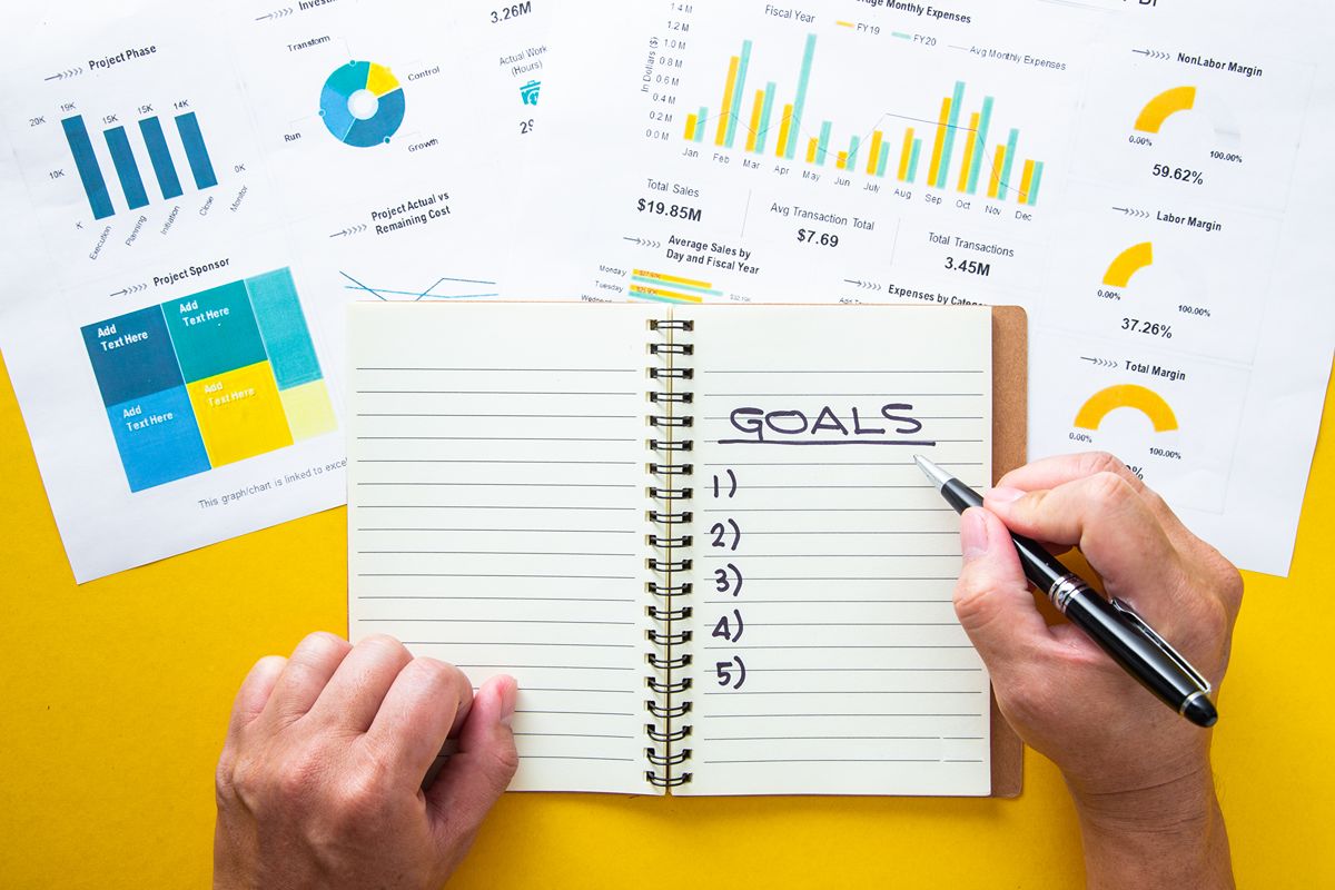 Person outlining marketing goals beside analytics reports, representing clear AEO deliverables, measurable progress, and strategic planning