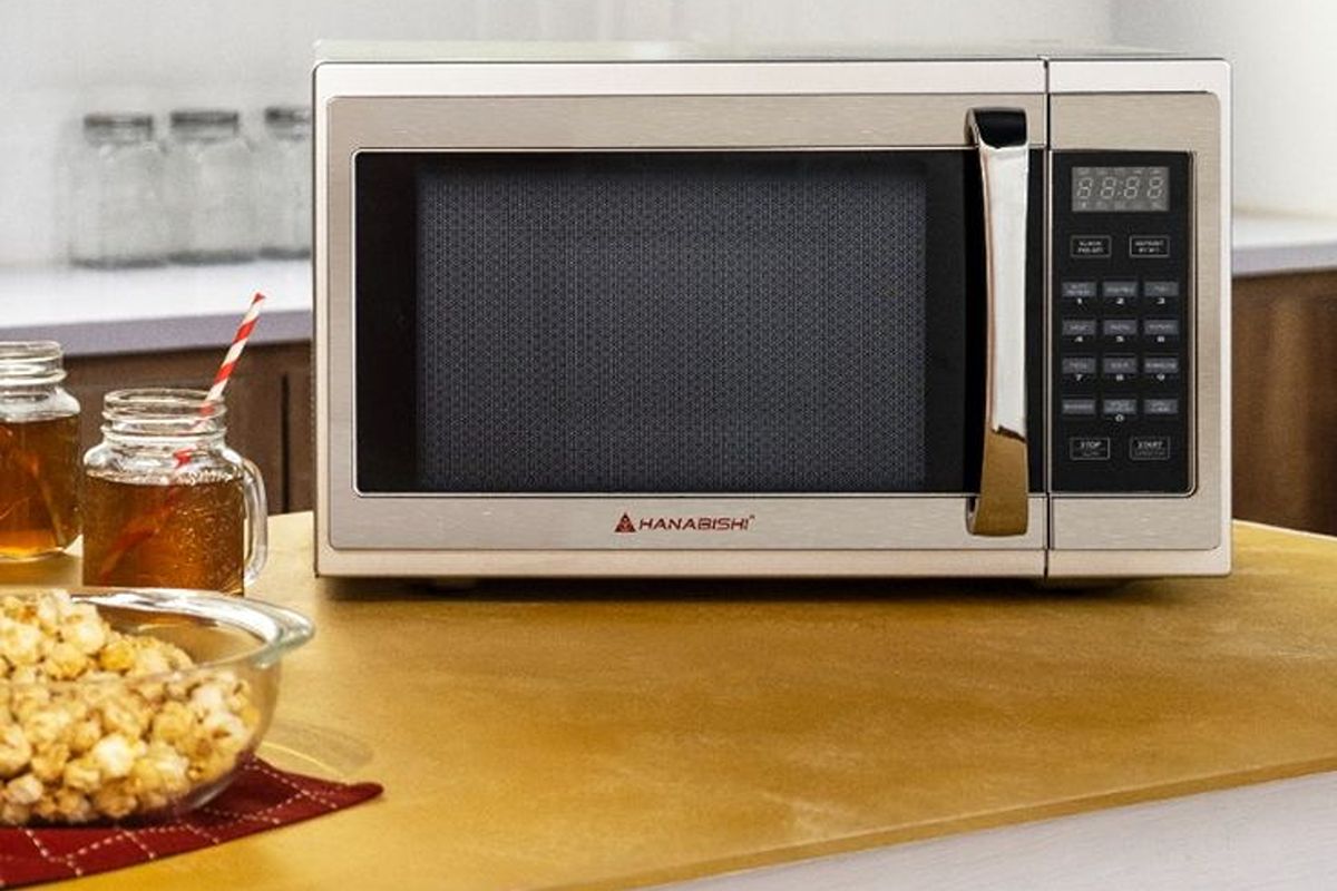 Hanabishi microwave oven with digital controls beside popcorn and drinks