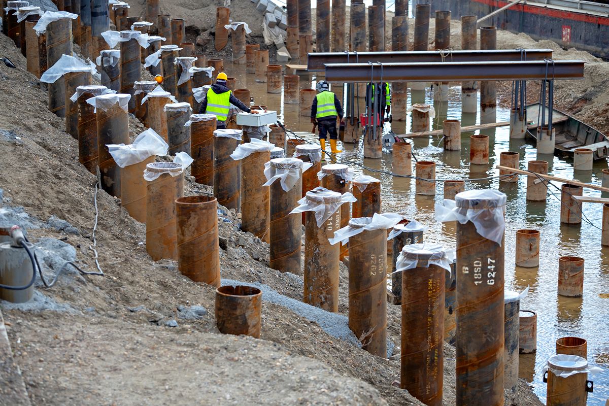Construction workers reviewing sheet pile materials for infrastructure foundation work