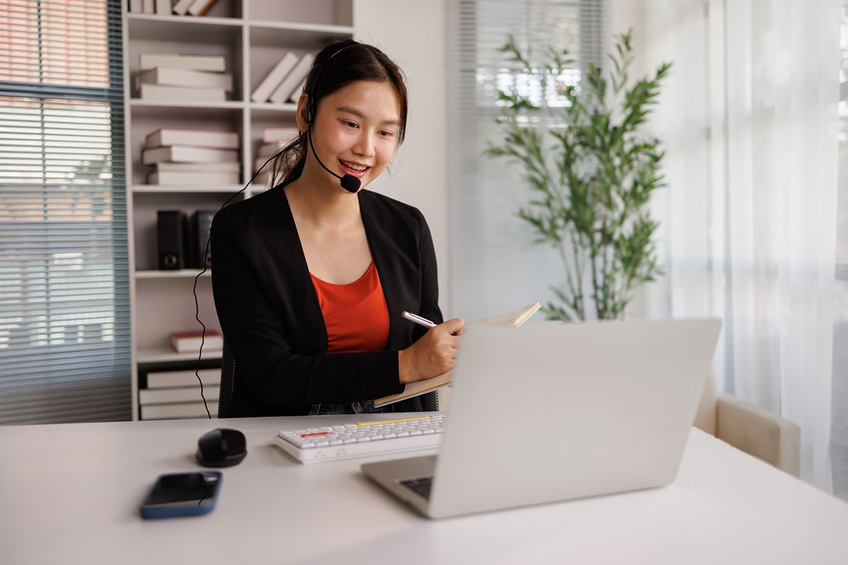 Healthcare virtual assistant wearing a headset while managing clinic support tasks from a laptop
