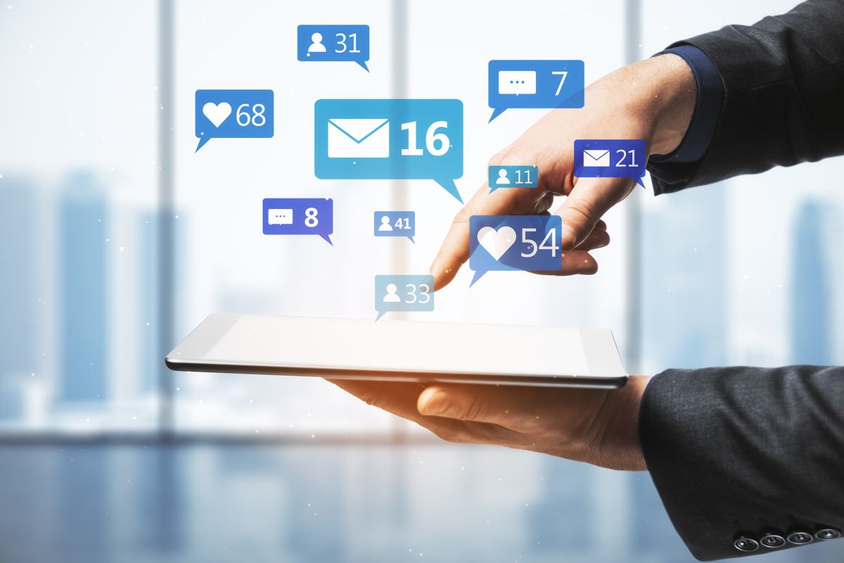 Business professional using a tablet surrounded by social media notifications for likes, messages, and followers